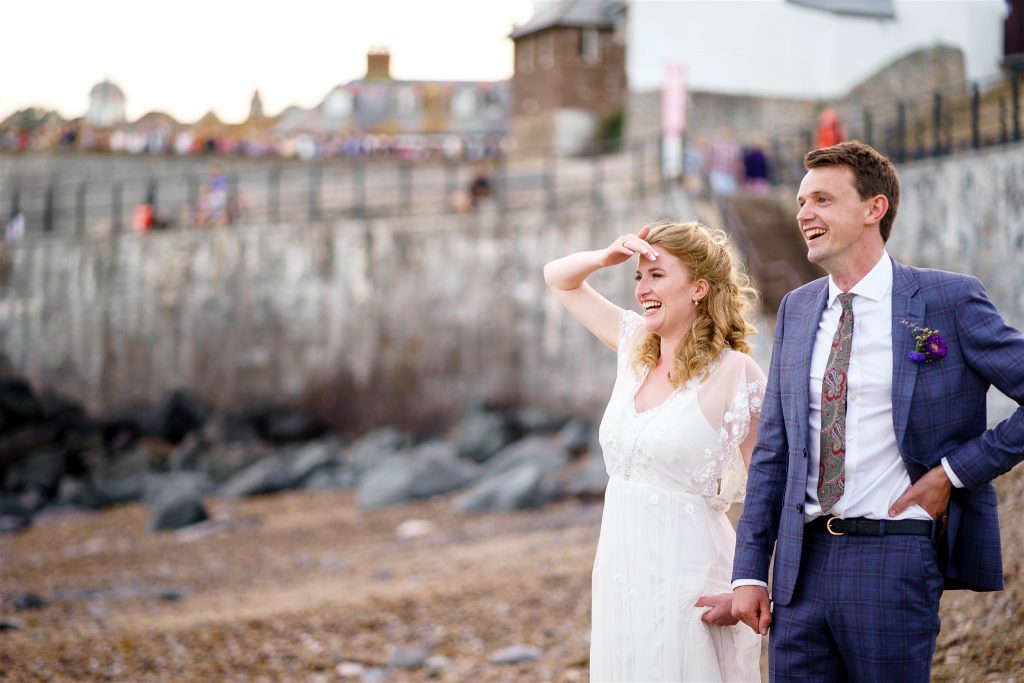 Wedding couple looks out to sea from Lyme Regis beach (South West of England).