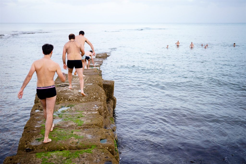 Group of men in boxers walking along the sea wall in Lyme Regis (South West of England).