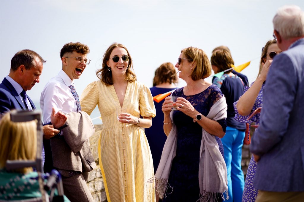 Wedding guests laughing outside the venue - Marine Theatre, Dorset.