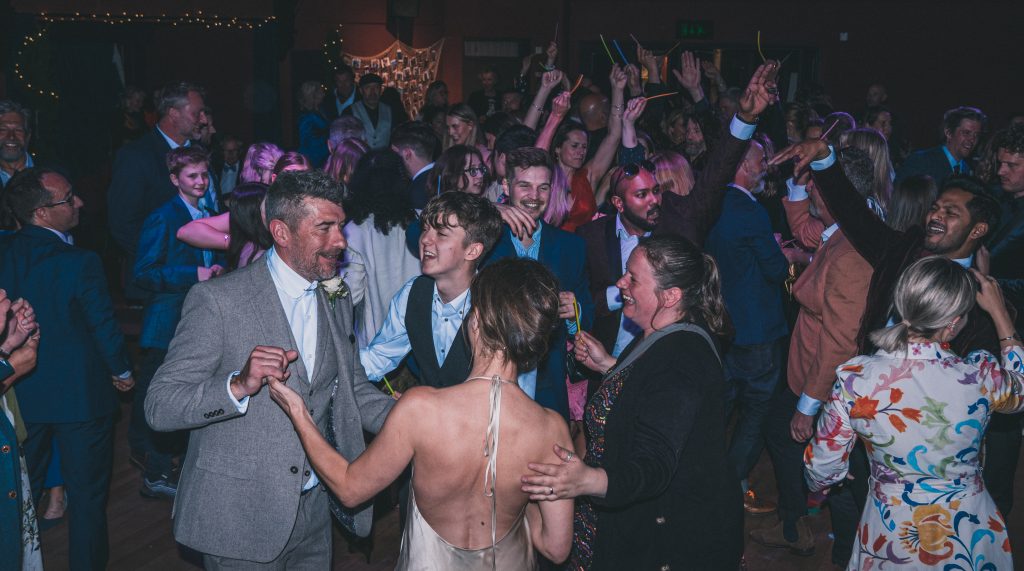 Bride and groom dancing with guests at their wedding at the Marine Theatre (South West of England).